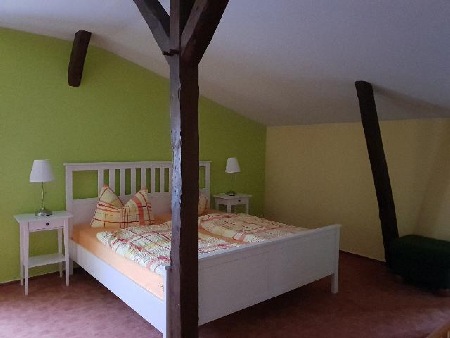 Schlafzimmer der Obergeschosswohnung mit grünen Wänden und alten Balken