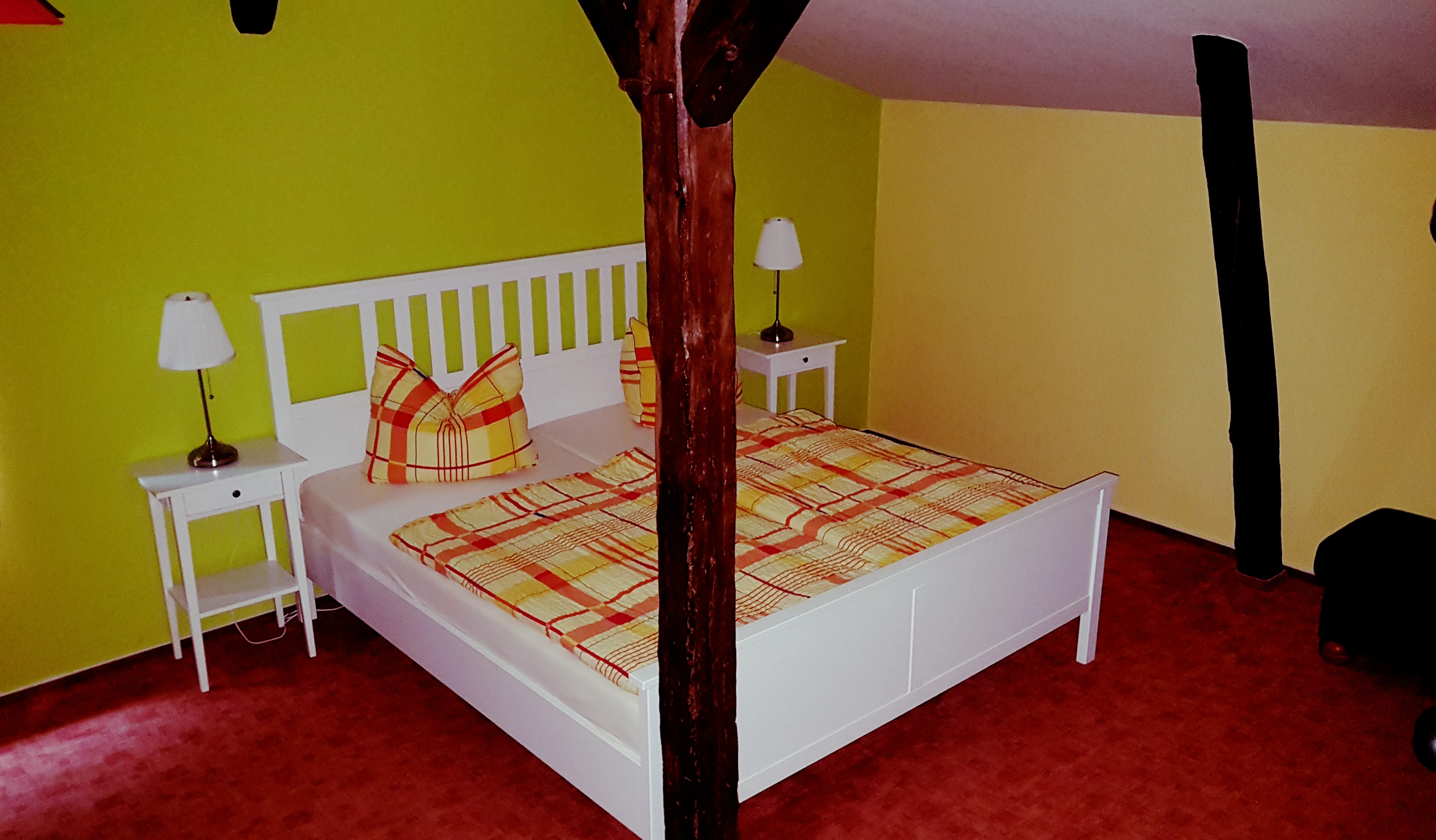 Hauptschlafzimmer der Obergeschosswohnung mit Doppelbett, Schrank, Nachtschränken und alten Balken